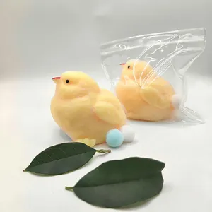 Detailed view of yellow fuzzy chick squishy toys with clear packaging bag and green leaves