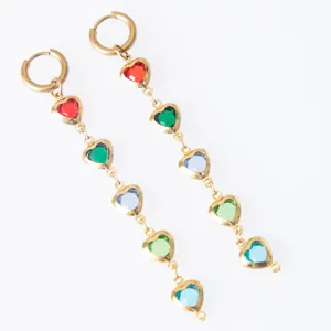 Close-up of gold-plated dangling earrings featuring colorful heart-shaped glass stones