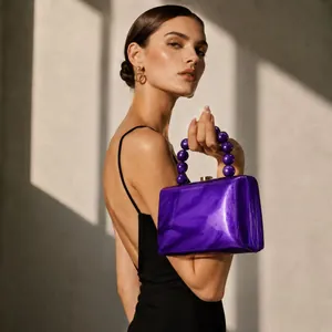Élégant sac de soirée en acrylique violet avec poignée perlée tenu par un mannequin