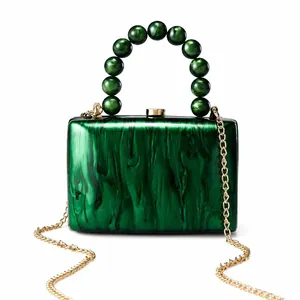 Gros plan d'une pochette de soirée en acrylique marbré vert avec poignée perlée et chaîne