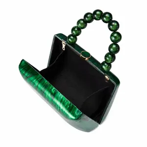 Vue détaillée du sac de soirée ouvert en acrylique marbré vert avec doublure noire.