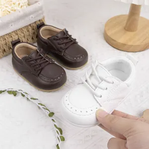 Detailansicht weißer Babyschuhe mit weicher Sohle und dekorativen Nähten aus Leder.