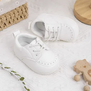 Detailansicht weißer Lauflernschuhe mit weicher Sohle und Schnürung auf einem Teppich.