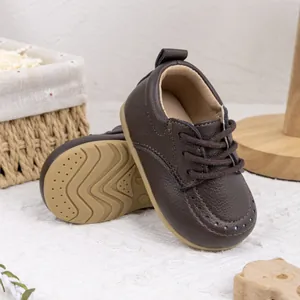 Nahaufnahme brauner Baby-Lederschuhe mit weicher rutschfester Gummisohle und Schnürung