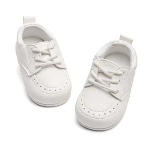 Nahaufnahme von weißen Kunstleder-Babyschuhen mit weichen Sohlen und Schnürdesign