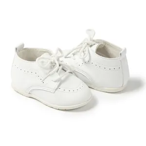 Nahaufnahme von weißen Babyschuhen mit Brogue-Details und weichen Antirutschsohlen