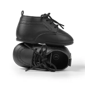 Nahaufnahme von mattschwarzen Leder-Babyschuhen mit Schnürdesign und Brogue-Details