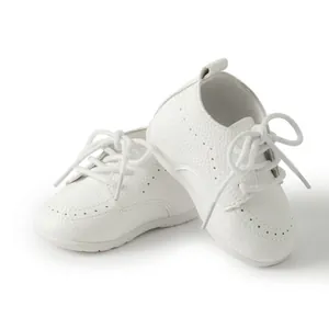Nahaufnahme der weißen Baby-Lederschuhe mit weichen Sohlen und Brogue-Details.