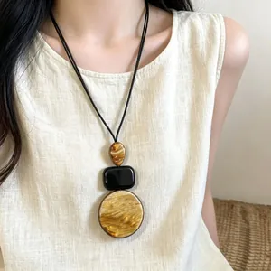 Long collier à pendentif géométrique en acrylique avec cordon noir sur un mannequin