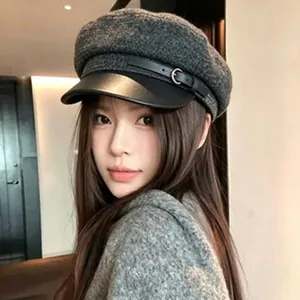 Chic gray wool newsboy cap with black leather brim worn by a female model.