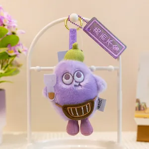 Primer plano de un llavero de berenjena de peluche morado con gorro y riñonera mini.