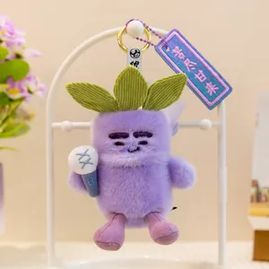 Primer plano de un lindo llavero de peluche de fruta morada con hojas verdes y etiqueta.