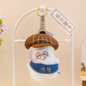 Primer plano de un adorable llavero de peluche blanco con gafas y gorro marrón