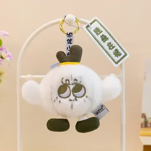 Detalle de un llavero de peluche blanco con una etiqueta bordada "Salud en la mano".