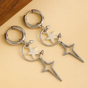 Détail de boucles d'oreilles punk argentées avec breloques étoile, croix et rivets.