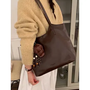 Vintage brown large capacity leather tote bag for women worn as an underarm shoulder bag