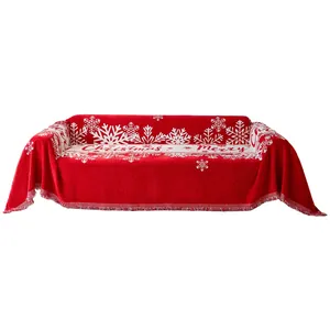 Funda de sofá navideña roja con patrones de copos de nieve blancos y elegantes flecos