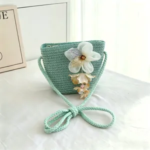 Detailed macro shot of mint green woven straw crossbody bag with floral ornament