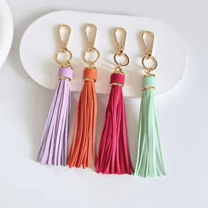 Detailed view of four colorful 10cm leather tassel keychains with gold lobster clasps.