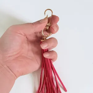 Detailed view of long pink faux leather tassel pendant accessory with golden swivel clasp