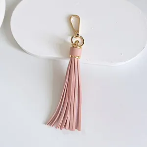 Detail view of a pink leather tassel bag charm with a glossy gold-colored metal clasp