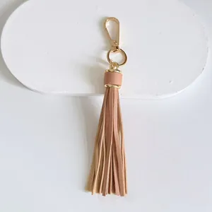Detailed view of peach leather tassel charm with golden lobster clasp and ring