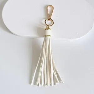 Detail view of 10cm white faux leather tassel with elegant gold-tone metal clasp