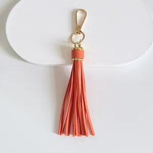 Detailed view of 10cm bright orange leather tassel keychain charm with gold lobster clasp