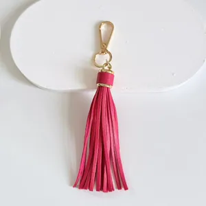 Detailed view of a hot pink leather tassel keychain with golden metal clasp charm