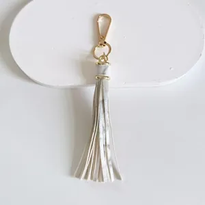 Detailed macro view of 10cm white leather tassel keychain with polished gold lobster clasp