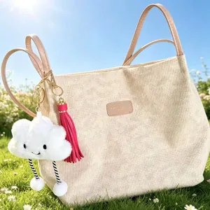 Detailed macro view showing a 10cm pink leather tassel keychain and soft cloud charm