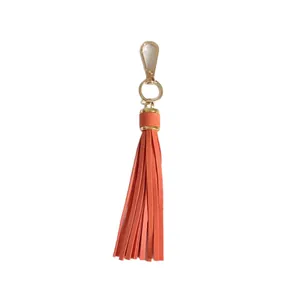 Vibrant orange leather tassel keychain bag charm featuring elegant gold-tone metal clasp
