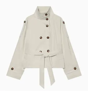 Detailed view of cream double-breasted short trench coat with waist tie and stand collar