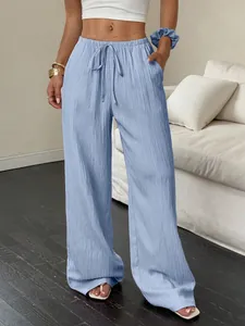 Close-up detail of light blue textured wide-leg trousers with elastic drawstring waist.
