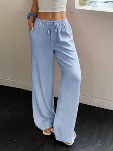 Detailed view of light blue wide-leg trousers with textured elastic drawstring waist