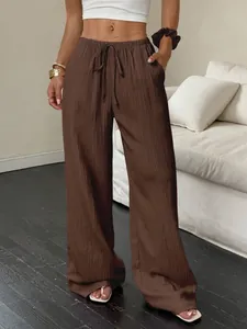 Close-up of brown textured wide-leg casual pants with drawstring waist in a home setting
