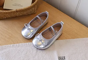 Close-up of silver girls' Mary Jane flats with bow detail on a wooden surface