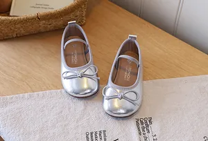 Close-up macro view of shiny silver girls ballet flats featuring an elegant bow knot detail