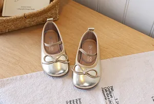 Detail shot of shimmering golden girls princess flat shoes with elegant bow accent