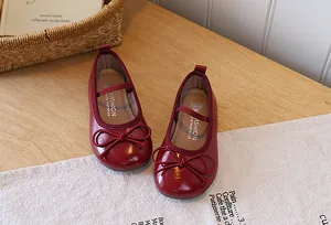 Close-up detail of red girl's Mary Jane shoes with elegant bow and patent finish