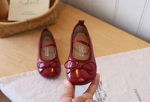 Close-up detail of red patent leather girl's princess shoes featuring a sweet bowknot