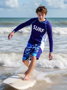Garçon surfant avec un rashguard à manches longues et un short de bain à motifs à la plage