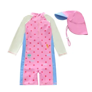 Detail van een roze kinderzwempak met lange mouwen, stippen en bijpassende zonnehoed