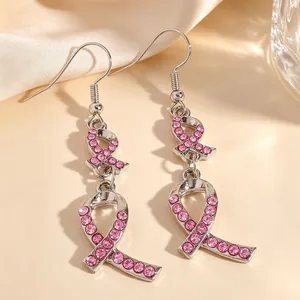 Gros plan de boucles d'oreilles ruban rose avec strass pour la sensibilisation au cancer.