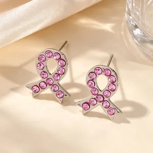 Gros plan de boucles d'oreilles ruban argentées avec cristaux roses pour la sensibilisation.