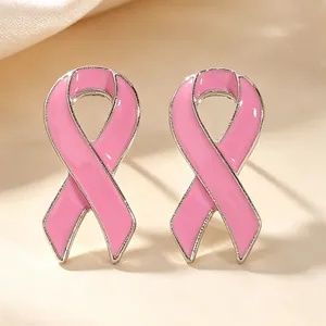 Détail macro de boucles d'oreilles ruban en émail rose pour la lutte contre le cancer