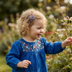 Close-up of cute floral pattern hair clips on a smiling young girl in a garden.