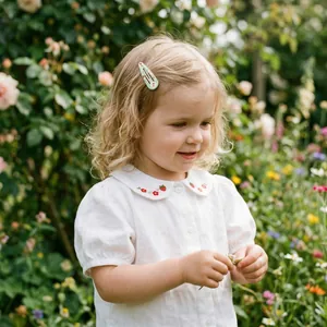 Close-up of a cute green floral hair clip worn by a toddler girl in a garden setting