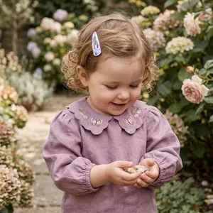 Cute toddler girl wearing a colorful painted teardrop hair clip in a garden setting