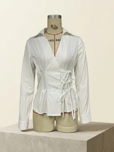 Detailed view of white long-sleeved shirt featuring side-tie waist design